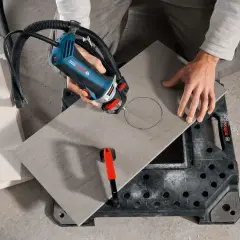 Persona cortando porcelánico con una sierra de Bosch, creando un círculo perfecto para un proyecto de bricolaje.