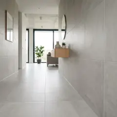 Pasillo moderno con paredes y suelo cubiertos de azulejos en horizontal o vertical. Una puerta de madera oscura a la izquierda y un mueble flotante con decoración a la derecha.
