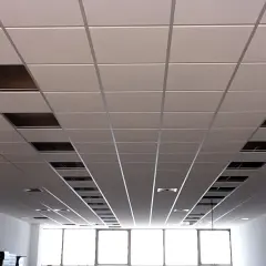 Un plenum falso techo modular con paneles blancos y rejillas metálicas visibles en algunos huecos.