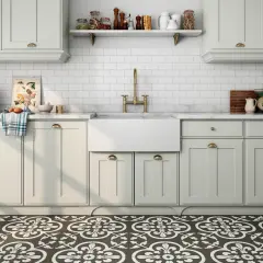 Cocina con suelo hidráulico de diseño floral. Encimera de mármol, fregadero blanco, grifería dorada y armarios claros.