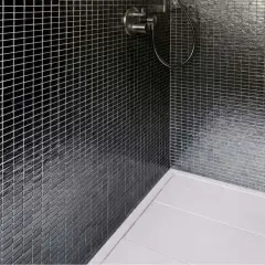 Ducha moderna con azulejos negros brillantes y plato de ducha blanco. La **resina epoxi** en la ducha garantiza un acabado impecable y duradero.