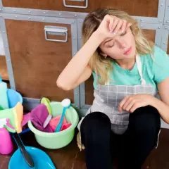 Mujer agotada tras una ardua jornada de limpieza, rodeada de productos y utensilios. Parece que la legia y el resto de la tarea la han dejado exhausta.