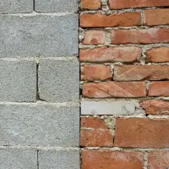 Muro de bloques de hormigón gris a la izquierda, ladrillos rojos desgastados a la derecha.