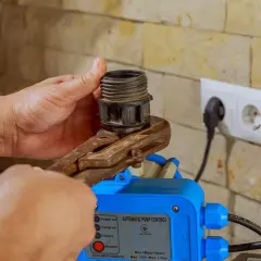 Mano ajusta un componente en un control automático de bomba, mostrando varios tipos de presostatos.