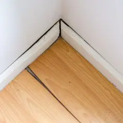 Esquina de habitación con parquet de madera con juntas abiertas. Guía para saber como recuperar el parquet y arreglar estas separaciones.