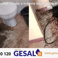 Baño inundado por atasco en la arqueta comunitaria. Se observa suciedad y una tubería de desatasco.