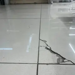 Baldosa rota en el suelo, con grietas y material desprendido. Una guía visual para saber como pegar una baldosa suelta.