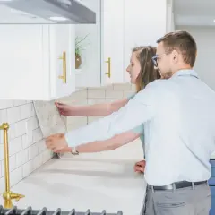 Pareja colocando azulejos en la cocina. ¿Cuánto cuesta alicatar una cocina? Elige el diseño perfecto para tu hogar.