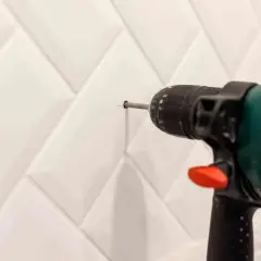 Taladro perforando azulejo blanco. Aprende cómo tapar agujeros en azulejos para un acabado perfecto.