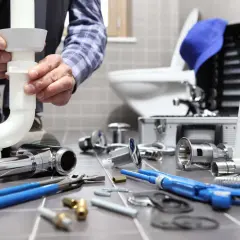 Fontanero instalando tuberías. ¿Cuánto vale desatascar una tubería? Herramientas y piezas de fontanería a la vista.