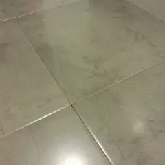 Detalle de la colocación de cerámica gris en un suelo, mostrando las juntas finas y el acabado mate.