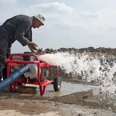 Hombre trabajando con una bomba de agua que lanza un chorro potente. A pesar de que se puede andar con la bomba de agua rota, él la mantiene en funcionamiento.