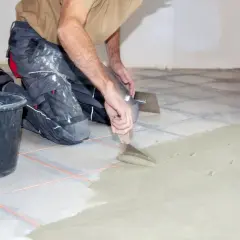 Un albañil aplica cemento para evitar que se levanten las baldosas del suelo.