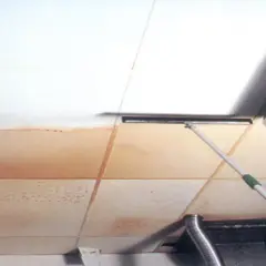 Limpiando manchas de agua en placas de techo desmontable con una mopa.