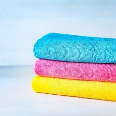 Tres paños apilados de tejido microfibra: azul, rosa y amarillo.