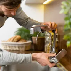 Man installing a faucet. ¿Cuánto cuesta poner un regulador de presión de agua?