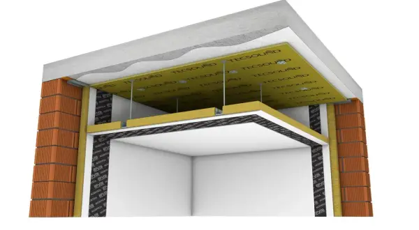 Detalle constructivo de aislamiento acústico. Se observa la distancia entre forjado y falso techo, con materiales aislantes y placas de yeso.