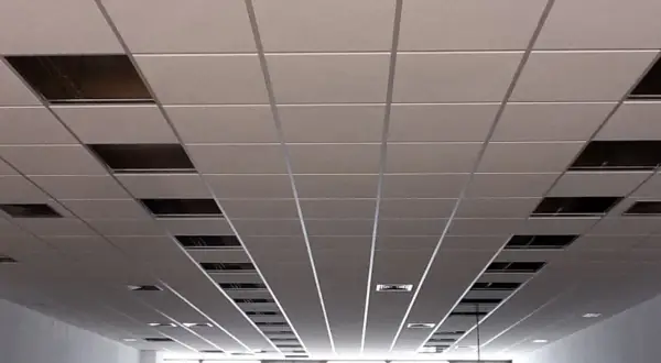 Un plenum falso techo modular con paneles blancos y rejillas metálicas visibles en algunos huecos.