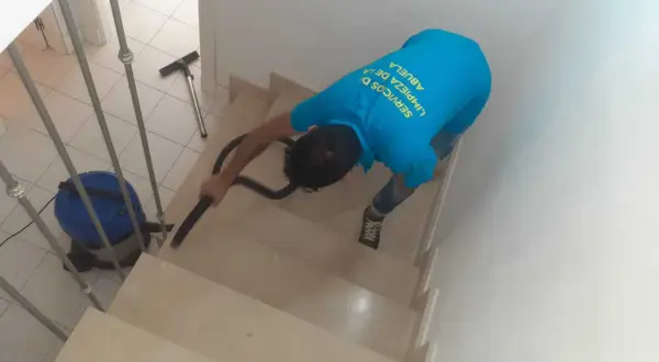 Un trabajador aspira escaleras para quitar polvo de obra.