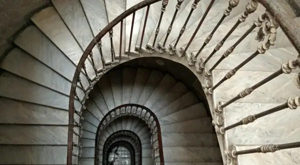 Escaleras de caracol de mármol con barandilla de hierro forjado. Un detalle de limpieza de escaleras de mármol revela su belleza clásica.