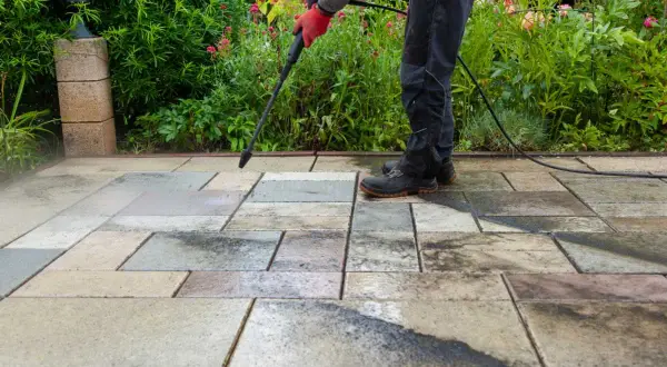 Persona realiza limpieza de patios con hidrolavadora, dejando las baldosas relucientes.