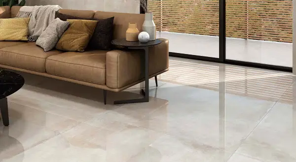 Elegante salón con sofá de cuero y suelo de gran formato, ideal para colocar baldosas.