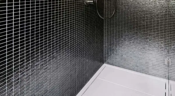 Ducha moderna con azulejos negros brillantes y plato de ducha blanco. La **resina epoxi** en la ducha garantiza un acabado impecable y duradero.