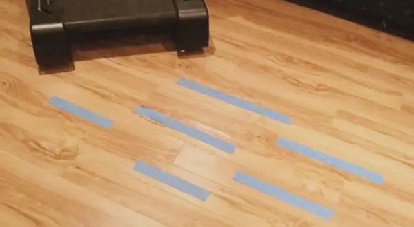 Marcando con cinta azul las áreas del parquet dañado por humedad para repararlo.