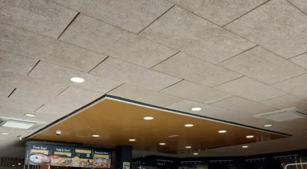 Techo celenit con paneles texturizados y luces empotradas, creando un ambiente moderno y acogedor.