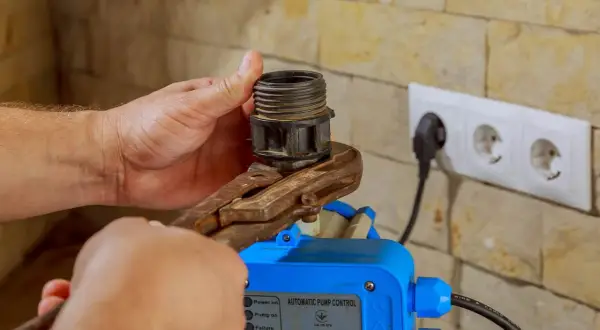 Mano ajusta un componente en un control automático de bomba, mostrando varios tipos de presostatos.