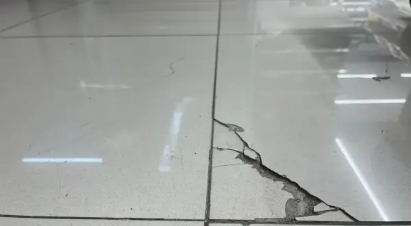 Baldosa rota en el suelo, con grietas y material desprendido. Una guía visual para saber como pegar una baldosa suelta.