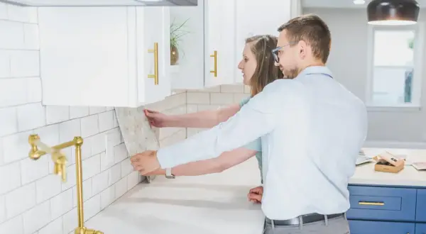 Pareja colocando azulejos en la cocina. ¿Cuánto cuesta alicatar una cocina? Elige el diseño perfecto para tu hogar.