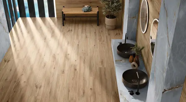 Baño moderno con suelo porcelánico imitando madera. Mueble de lavabo doble con lavabos sobre encimera y grifería negra.