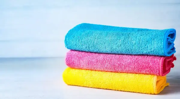 Tres paños apilados de tejido microfibra: azul, rosa y amarillo.