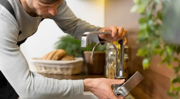 Man installing a faucet. ¿Cuánto cuesta poner un regulador de presión de agua?