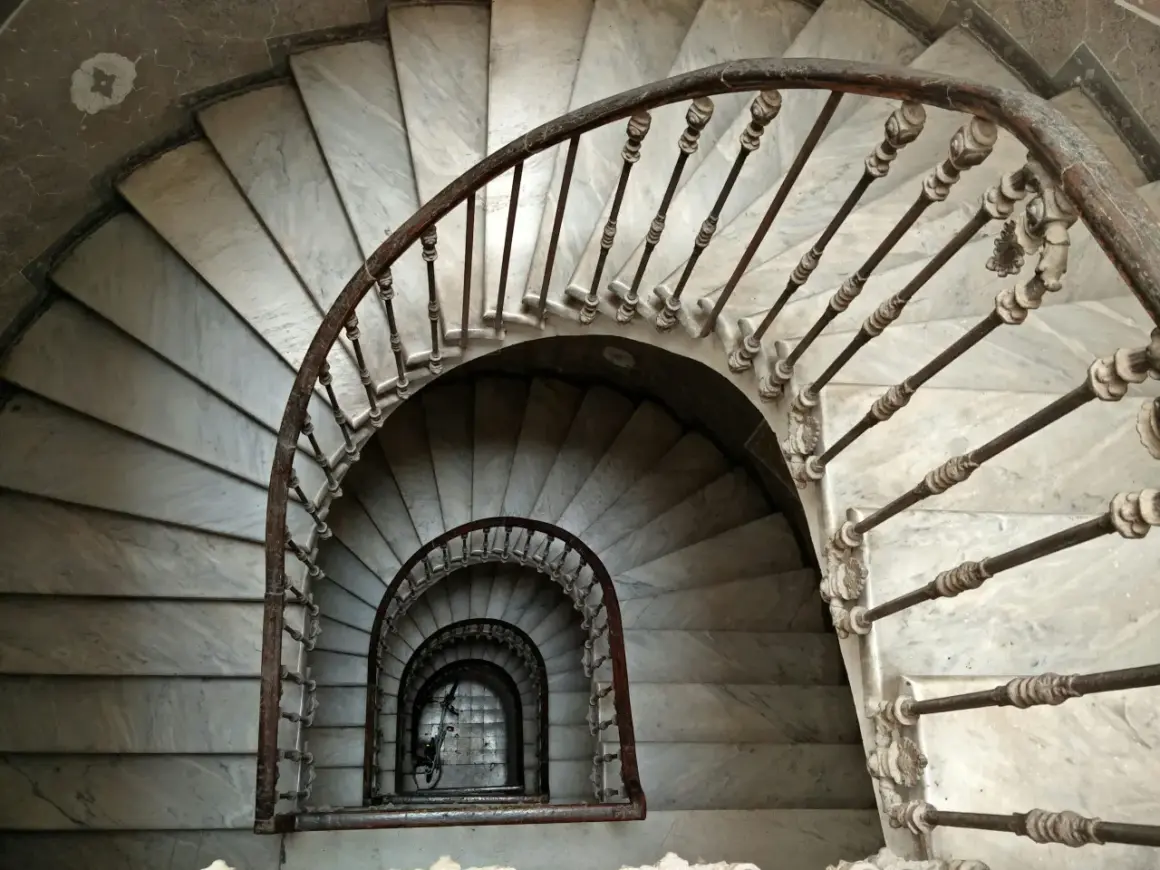 Escaleras de caracol de mármol con barandilla de hierro forjado. Un detalle de limpieza de escaleras de mármol revela su belleza clásica.