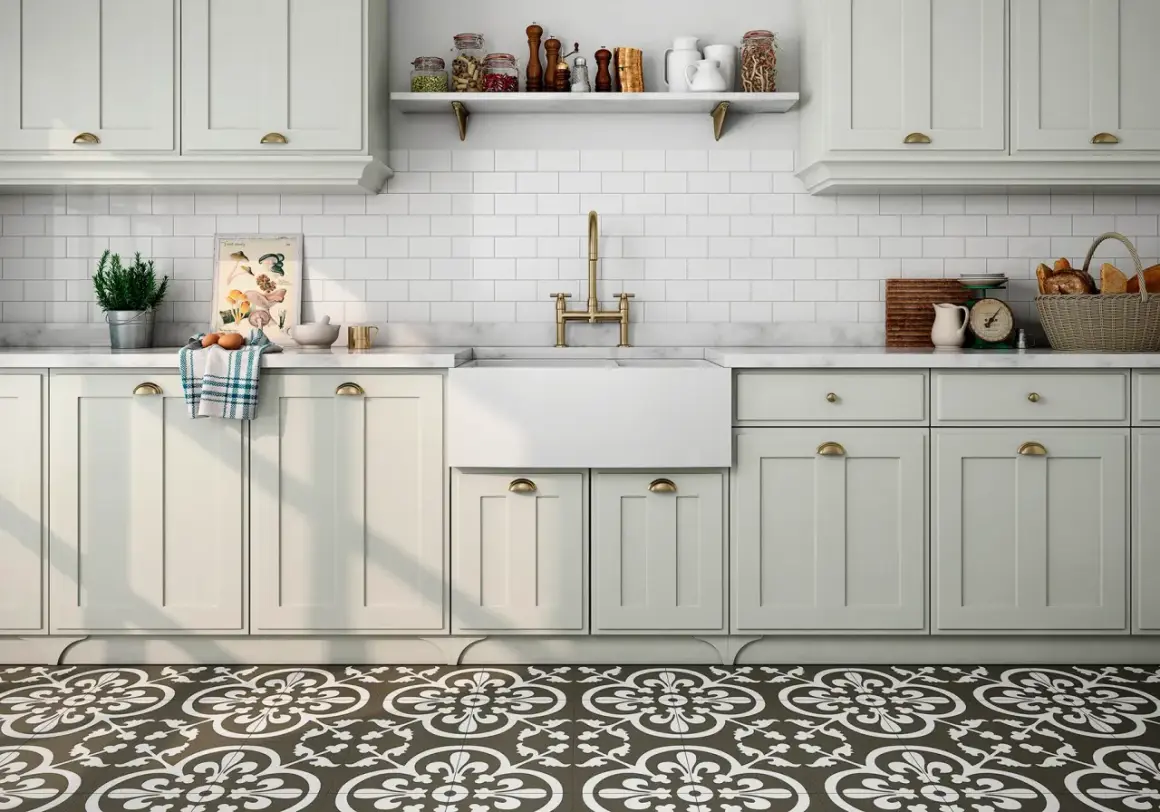 Cocina con suelo hidráulico de diseño floral. Encimera de mármol, fregadero blanco, grifería dorada y armarios claros.