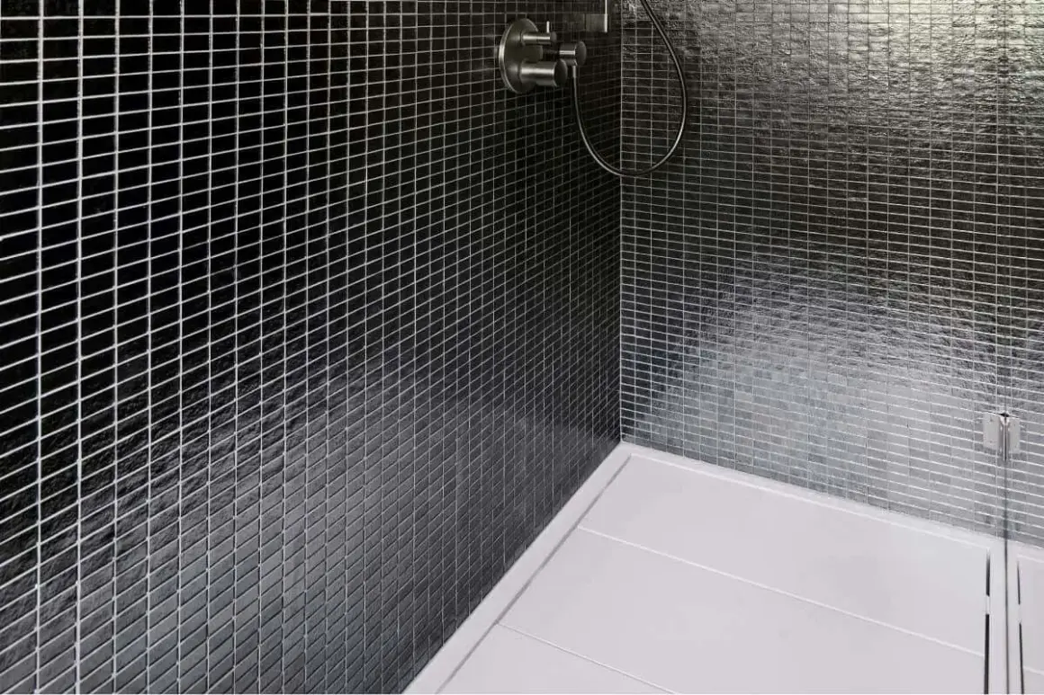 Ducha moderna con azulejos negros brillantes y plato de ducha blanco. La **resina epoxi** en la ducha garantiza un acabado impecable y duradero.