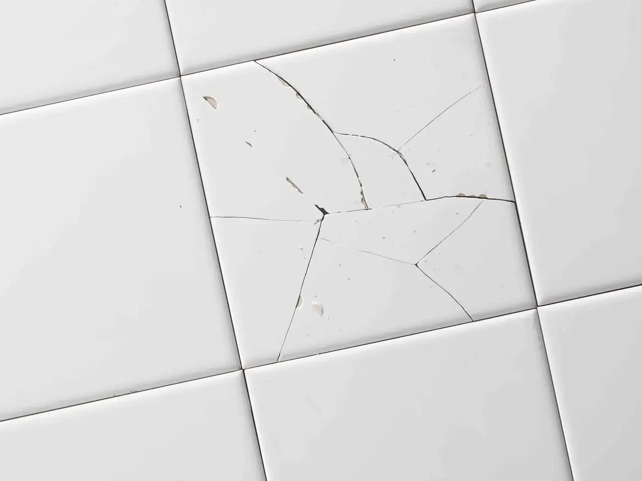 Azulejo blanco con grietas y desconchones. Aprende c&oacute;mo arreglar un azulejo roto para restaurar su apariencia.