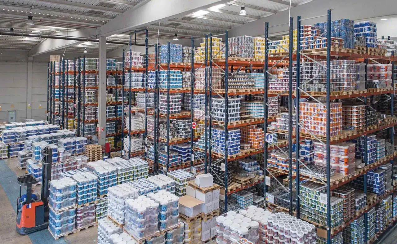 Estanter&iacute;as llenas de latas de pintura y otros productos, listas para su distribuci&oacute;n. El orden y la limpieza del almac&eacute;n son clave.