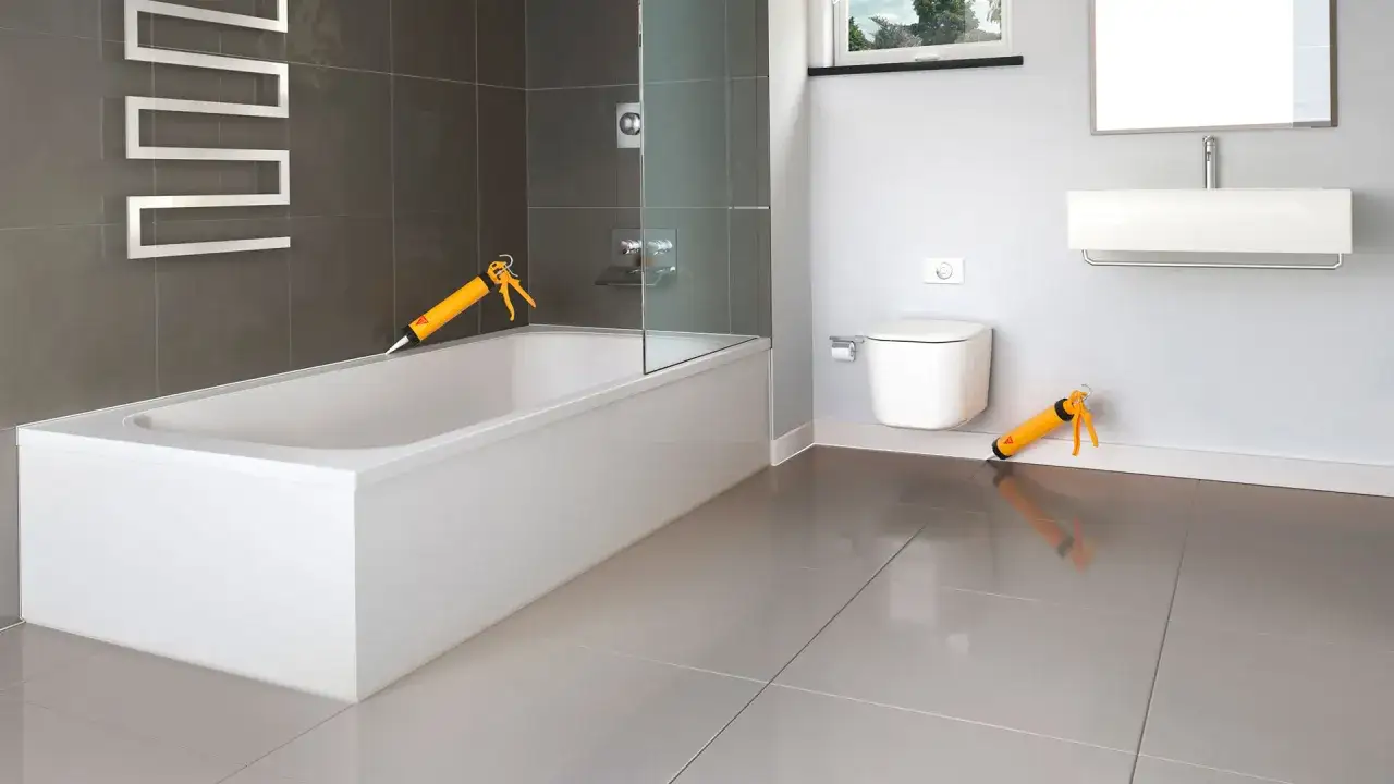Pistolas de silicona listas para sellar el borde de la ba&ntilde;era, un paso clave en como poner azulejos en un ba&ntilde;o.