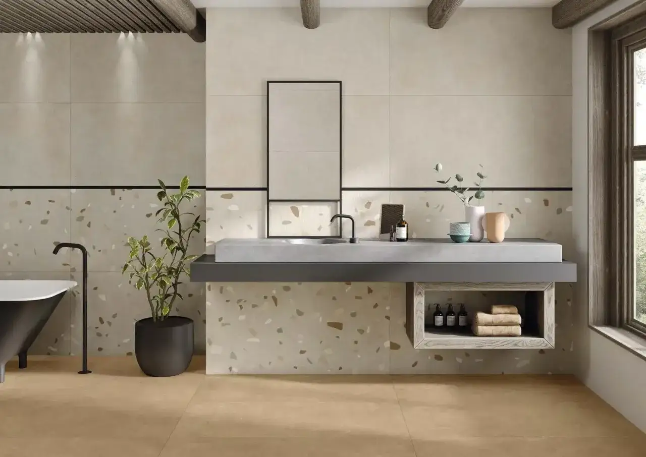 Ba&ntilde;o moderno con paredes de azulejo y baldosa de terrazo. Lavabo flotante, ba&ntilde;era negra y planta.