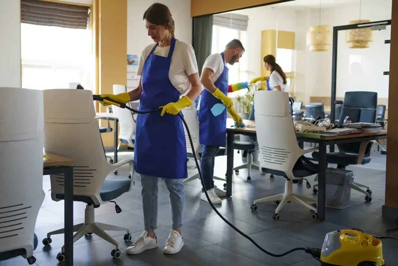 Equipo de limpieza en acci&oacute;n, demostrando sus funciones. Una auxiliar de limpieza usa vapor para desinfectar sillas de oficina.