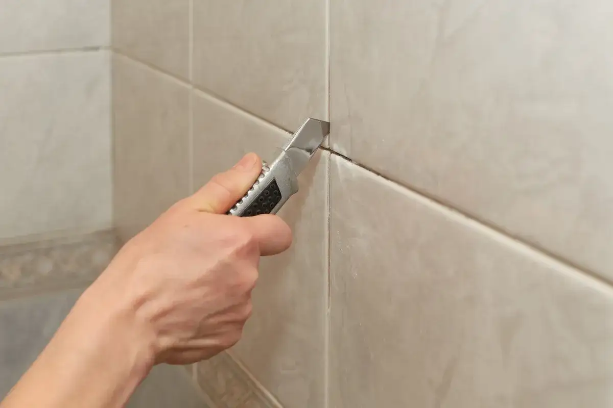 Mano con cúter para quitar juntas de azulejos.