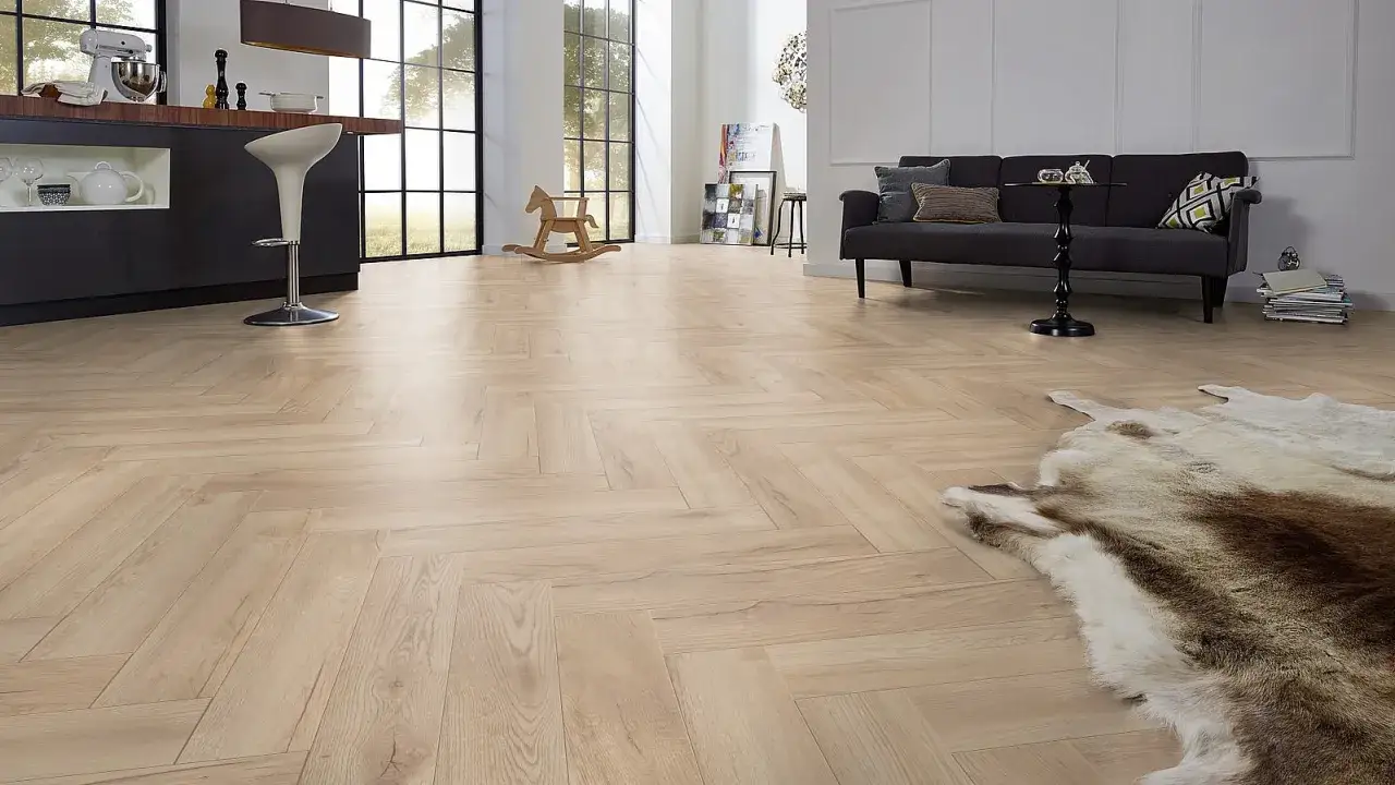 Elegante sal&oacute;n con suelo de madera en espiga. Una alfombra de piel y un sof&aacute; oscuro a&ntilde;aden calidez.