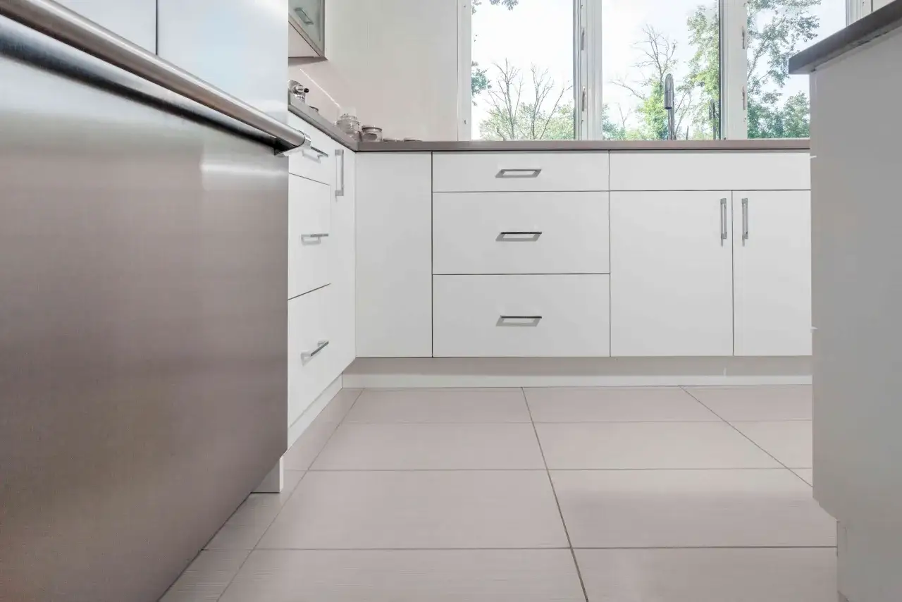 Cocina moderna con suelo de gres, un material resistente y est&eacute;tico. Armarios blancos y electrodom&eacute;sticos de acero inoxidable.