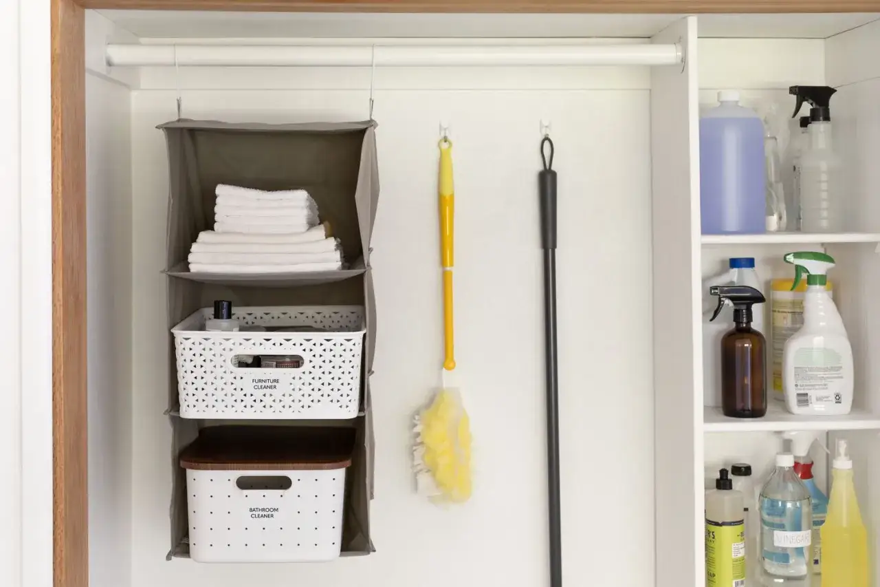 Organizaci&oacute;n para la limpieza del ba&ntilde;o: toallas, cestas con productos y escobas.
