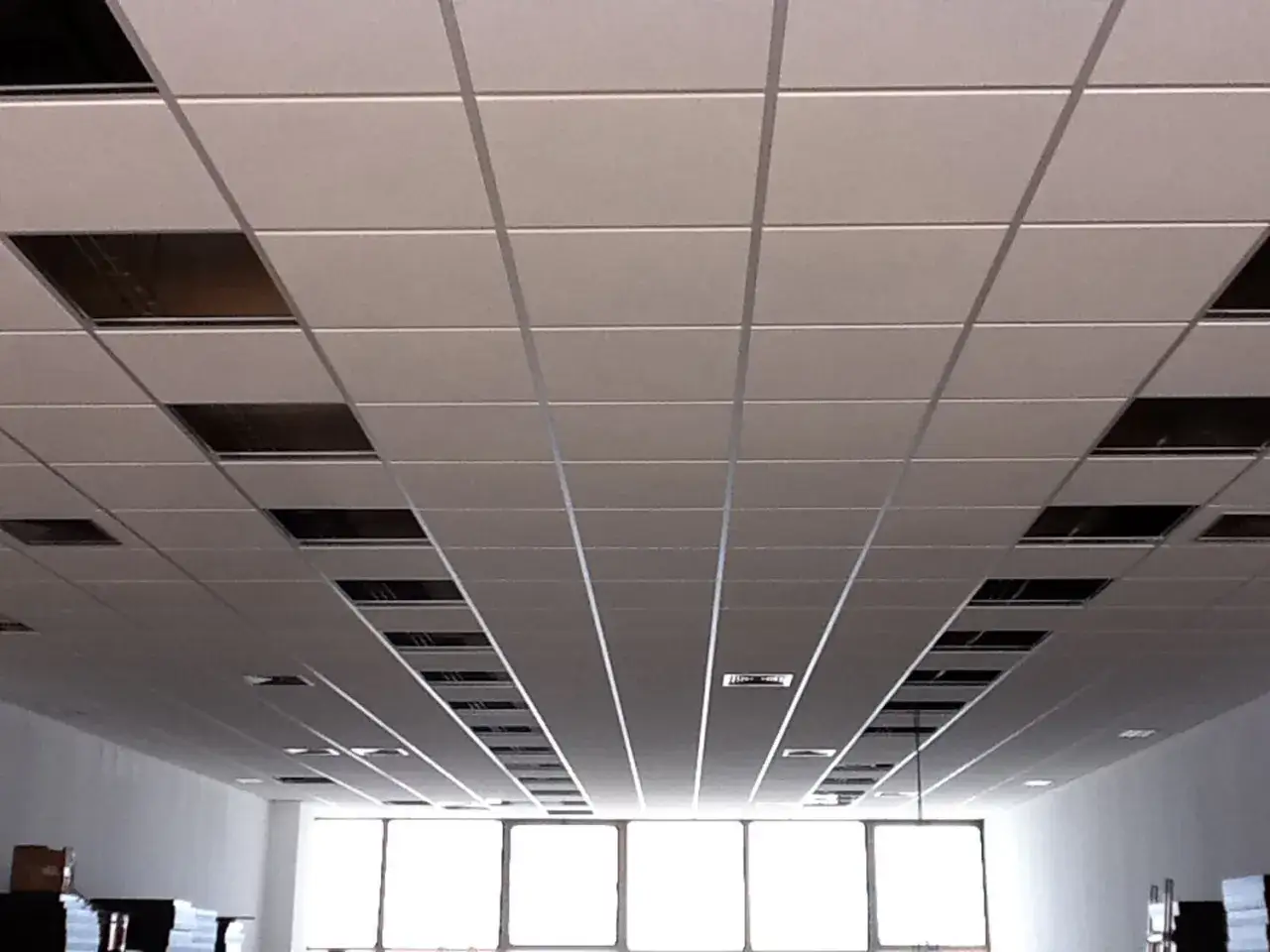 Techo modular con paneles cuadrados y rectangulares. Se aprecia la distancia entre forjado y falso techo, con huecos para instalaciones.