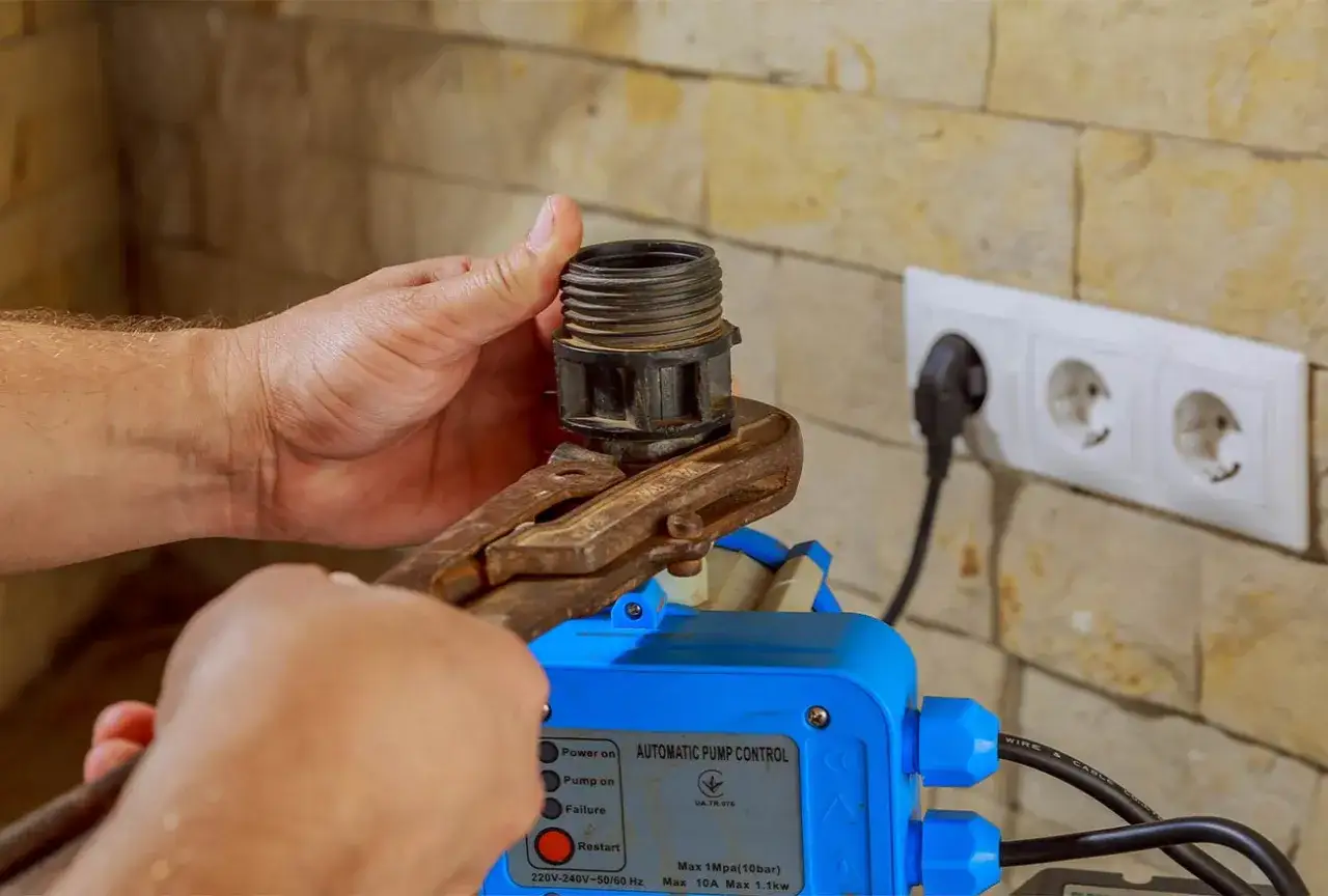 Mano ajusta un componente en un controlador de bomba autom&aacute;tico, que es un tipo de presostato.