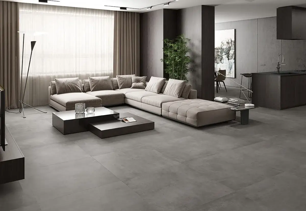 Elegante sal&oacute;n con sof&aacute; modular beige y mesas de centro oscuras sobre suelo de baldosas grises, mostrando varios tipos de suelo interior.